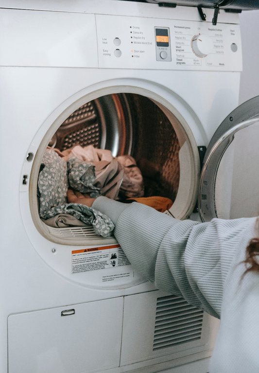 woman reaching into laundry machine full of clean clothes
